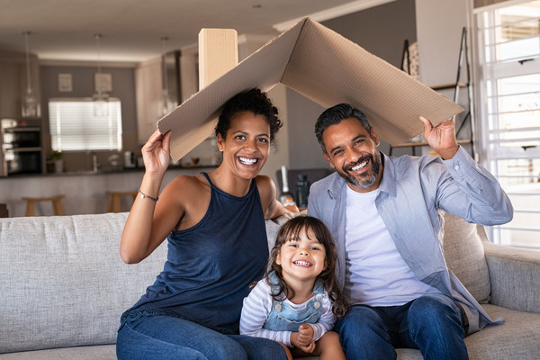 Family of three on a couch under cardboard roof