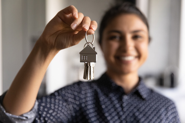 smiling person holds house keys in foreground