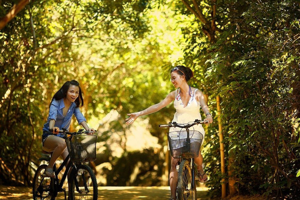 two young women, one with her right arm raised, on bikes