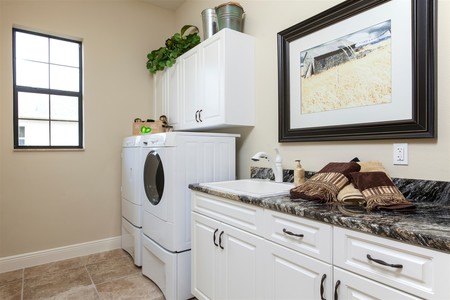 Laundry room is designed for work with generous countertop space, a sink and plenty of cabinetry for stoage